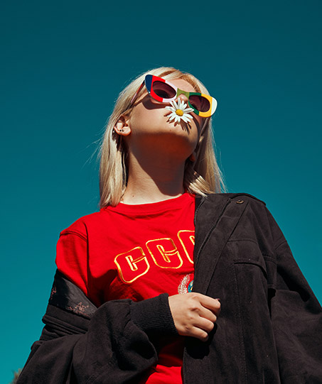 A young girl in vibrant sunglasses and a black denim jacket.